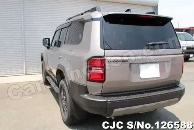 Rear three-quarter view of a gray SUV parked outside a metal-paneled building, showing tinted rear window and black bumper.